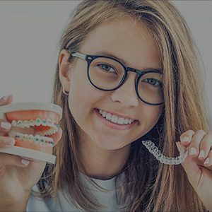 Woman holding Invisalign and braces in her hands